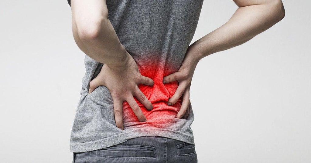 A person experiencing back pain while sitting on a couch.